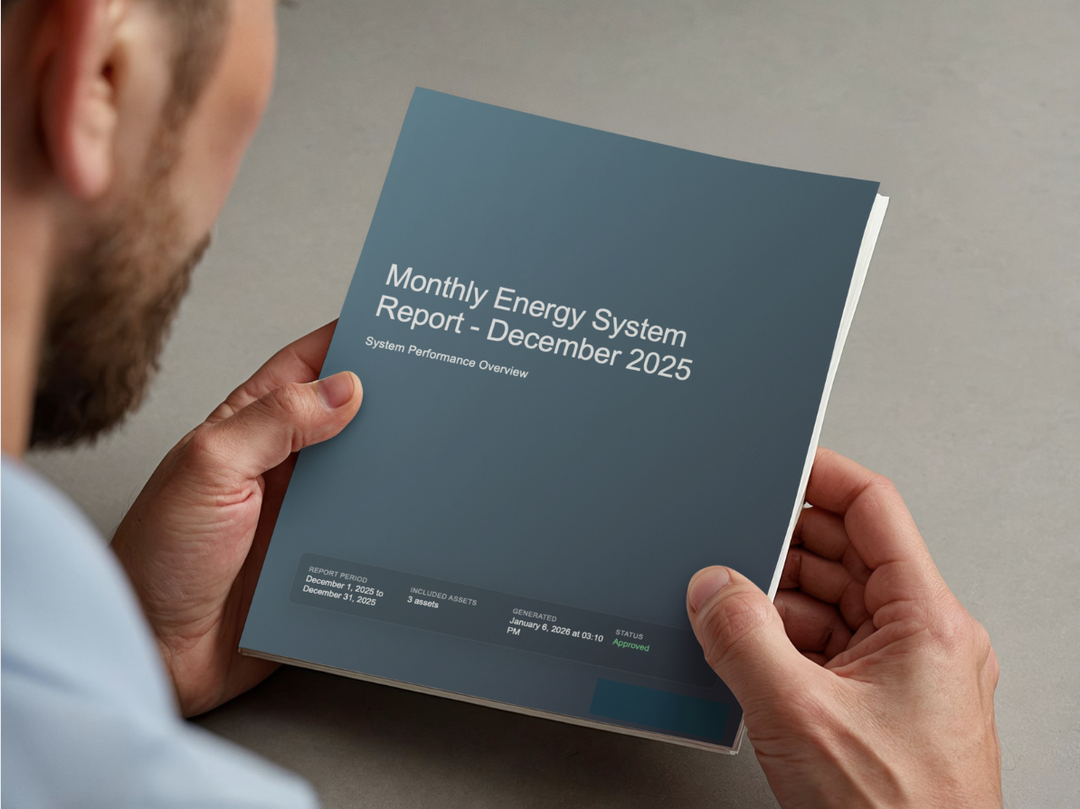 Man holding a printed report entitled 'Monthly Energy System Report - December 2025'